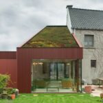 Umbau einer Garage zum Gartenzimmer mit roter Metallfassade und begrüntem Dach