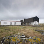 Einfamilienhaus in Holzbauweise mit schwarzem Dach an der Meeresküste der schottischen Insel Tiree