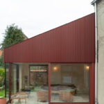 Neues Gartenzimmer mit roter Metallfassade und bodentiefen Fensterflächen