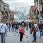 Touristen in Venedig mit Kreuzfahrtschiff im Hintergrund