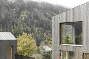 Einfamilienhaus am Hang von Naemas Architekten mit grau lasierter Lärchenholzfassade