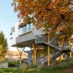 Wohnhaus auf gelben, gegabelten Metallpfeilern aufgeständert