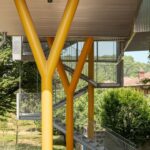 Wohnhaus auf gelben, gegabelten Metallpfeilern aufgeständert