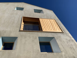 Wohnhaus aus monolithischem Mauerwerk mit Trichterfenstern und Holzschiebeläden