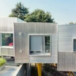 Aufgeständertes Wohnhaus mit gewellter Metallfassade