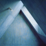 Innenansicht eines Dachbodens in einem A-förmigen Haus, komplett in Blautönen gestrichen, mit sichtbarer Holzmaserung und seitlichem Fenster, durch das Licht einfällt
