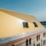Aufstockung mit goldfarbener Aluminiumfassade auf einem denkmalgeschützten Speichergebäude in Kiel