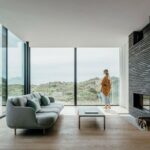 Wohnzimmer in einem Strandhaus mit raumhoher Glasfassade und Blick in die Dünenlandschaft