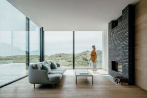 Wohnzimmer in einem Strandhaus mit raumhoher Glasfassade und Blick in die Dünenlandschaft