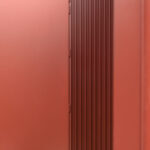 Tür in profilierter roter Metallfassade