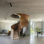 Wendeltreppe mit Holzverkleidung in einem Wohnraum mit viel Sichtbeton