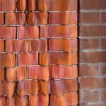 3D-gedruckte Fassadenelemente mit organischer Form und rötlicher Farbe, die an traditionelles Ziegelmauerwerk erinnert