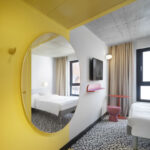 Hotelzimmer im Ibis Budget Münster mit gelben Farbakzenten und Wand und Decke