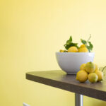 Schale mit Zitronen vor einer limonengrünen Wand