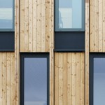 Die Fassade besteht aus vertikalen Lärchenholz-Brettern, die durch Fenster unterbrochen sind. Bild: © Frank Scholl