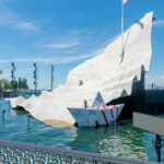 Überdimensionales Blatt Papier als Bühnenbild bei den Bregenzer Festspielen, daneben ein Papierboot