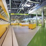 Gelbe Kassenterminals sowie verstreut angeordnete Geschirrstationen auf leuchtend grünem und silbrig-grauem Vinylboden.