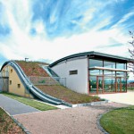 Die Wellenform des Kindergartens fügt sich harmonisch in den Geländeverlauf im länglichen Stadtteilpark und in die Hügellandschaft der Rhön ein.