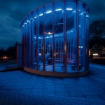 Strahlender Solitär: Nachts leuchtet der Holz-Glaspavillon in wasserblauer Anmutung.