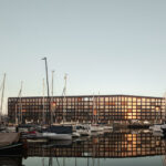 Wohngebäude Jonas' von Orange Architects am Hafen von IJburg mit Booten im Vordergrund
