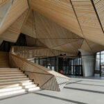 Treppenaufgang und prägnant geformte Holzdecke im Wohngebäude Jonas' von Orange Architects