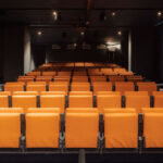 Kinosaal mit gelben Sitzen im Wohngebäude Jonas' von Orange Architects