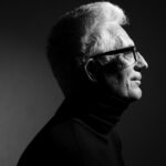 Älterer Mann im Profil mit schwarzem Rollkragenpullover und Hornbrille