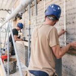 Bauarbeiter bearbeiten Stampflehm-Wand