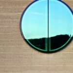 Stampflehmwand mit rundem Fenster am Ricola Kräuterzentrum