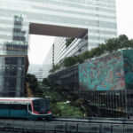 Projekt Cloud 11 in Bangkok von Snøhetta mit Gebäudeöffnung, grünen Hochgärten und Skytrain im Vordergrund