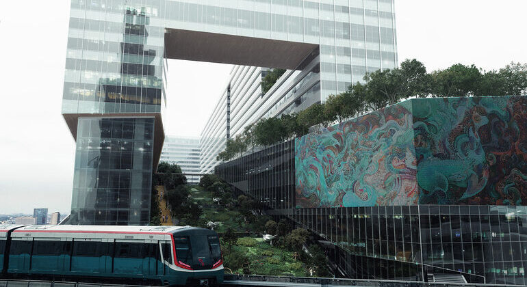 Projekt Cloud 11 in Bangkok von Snøhetta mit Gebäudeöffnung, grünen Hochgärten und Skytrain im Vordergrund