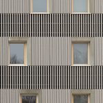 Eine vertikale Holzleistenfassade mit unterschiedlichen Leistenabständen strukturiert die Fassade in horizontale Bänder. Bild: David Franck