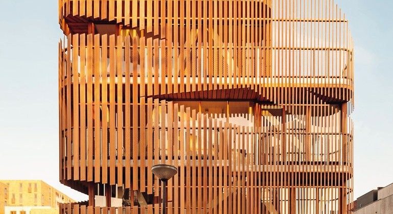 Zedernholz als Lamellenfassade vor geschosshoher Verglasung ermöglicht Tageslichteinfall im Doppelwohnhaus