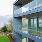 Die Kombination aus schmalen Zinkbändern und Glasflächen lässt das Gebäude zur Talseite hin leicht und schwerelos wirken. Bild: VMZINC | Paul Kozlowski