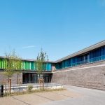 Spannungsreiche Kontraste aus Naturstein und farbigen Sonnenschutzlamellen für das Büro- und Lagergebäude der RAL.
