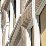 Die Stahlbetonfertigteile der vorgehängten, hinterlüfteten Fassade mit eingelegten Klinkerriemchen sind durch Passstücke aus hellem Beton verbunden. Bild: Florian Selig