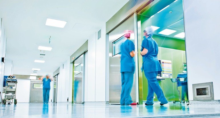 Krankenhausflur mit Pflegepersonal und Ärzten, überlichtete Fotographie. Bild: Glamox