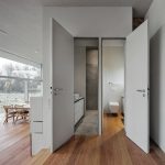 Eine WC- und eine Duschbad-Miniatur liegen auf erhöhter Eingangsebene hintereinander, beide mit Tageslicht: das WC an der Außenwand, das Duschbad innenliegend mit transluzenter Glaswand. Bild: Werner Huthmacher
