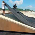 Die OSB-Dachplatten wurde mit dem Flächenkleber versehen, der die hier aufgelegte, großflächige EPDM-Plane windsogsicher fixiert. Bild: Carlisle