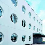 Weiße, glatte Hausfassade mit runden, großflächigen Fenstern. Bild: X ARCHITEKTEN ZT GmbH