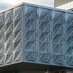 Hausecke mit silbrig-durchbrochener Fassade aus Aluminium-Verbundwerkstoff-Platten.