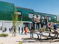 Kinder vor einem Grundschulzentrum mit grün-schillernder Keramikfassade