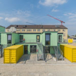 Gelbe Container vor grünem Haus.