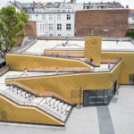 Goldene Kupferfassade und helle Treppen und Dachflächen.