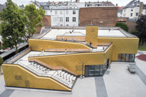 Goldene Kupferfassade und helle Treppen und Dachflächen.