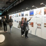 Besucher der Messe Architect@Work betrachten Präsentationwände, auf denen Projekte internationaler Architekten gezeigt werden